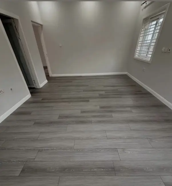 Suíte de casal com piso laminado em tom amadeirado quente e cabeceira moderna