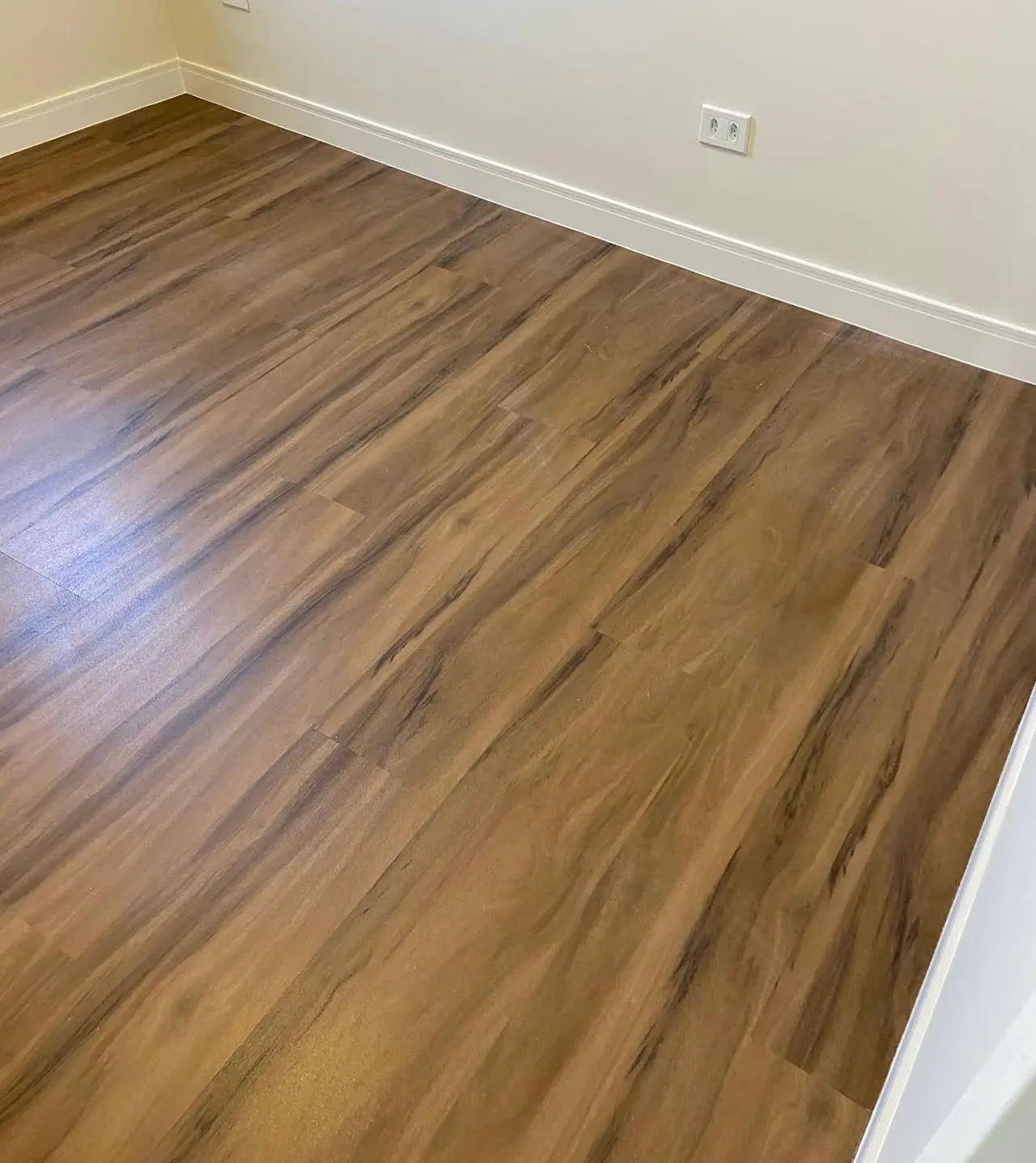 Quarto reformado com piso laminado e rodapé branco de poliestireno